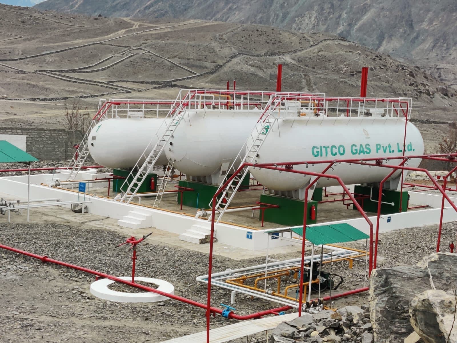 Three white bulk LPG storage tanks on engineered plinths at the Gitco Gas plant, surrounded by a red fire-hydrant ring main.